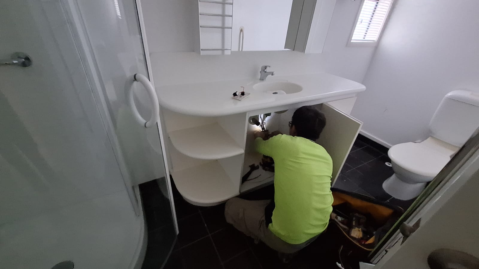 TradePlus plumber connecting the waste and tapware under a new bathroom vanity