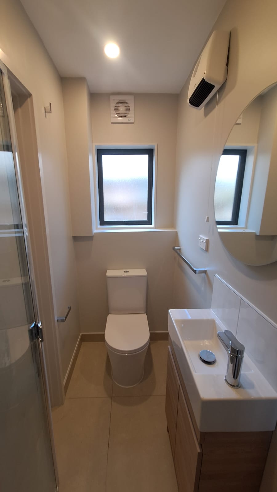 Completed Auckland bathroom renovation with new glass shower enclosure, slimline vanity, close-coupled toilet and large-format floor tiles